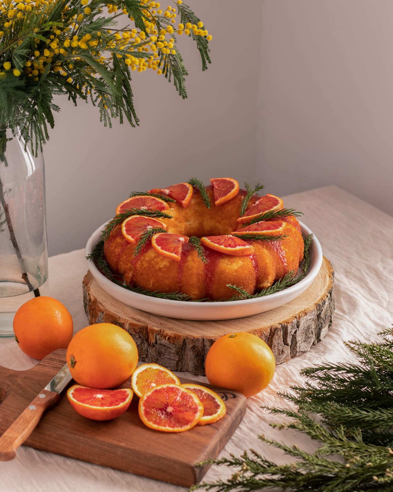 Blood orange bundt cake garnished with citrus slices on wood board
